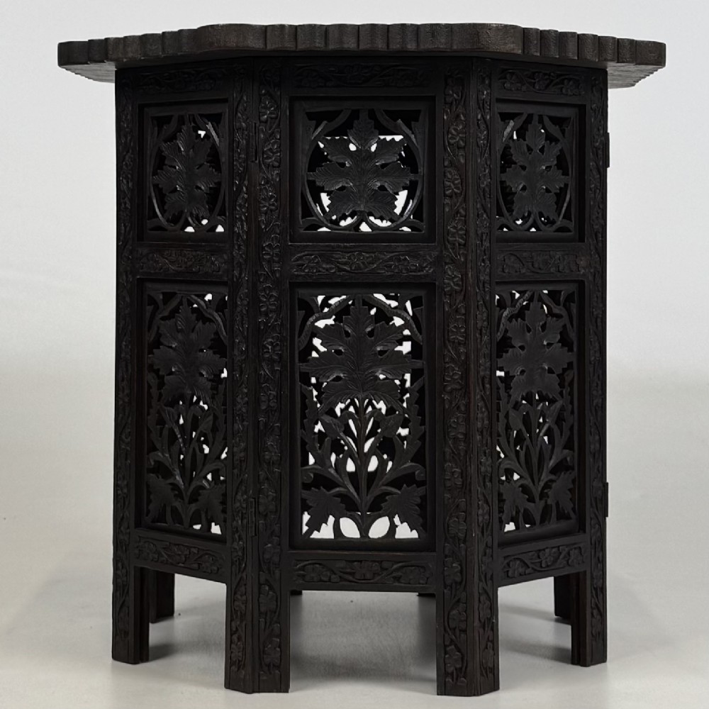 A dark brown octagonal wooden side table featuring intricate hand-carved foliate openwork panels across every side. View V