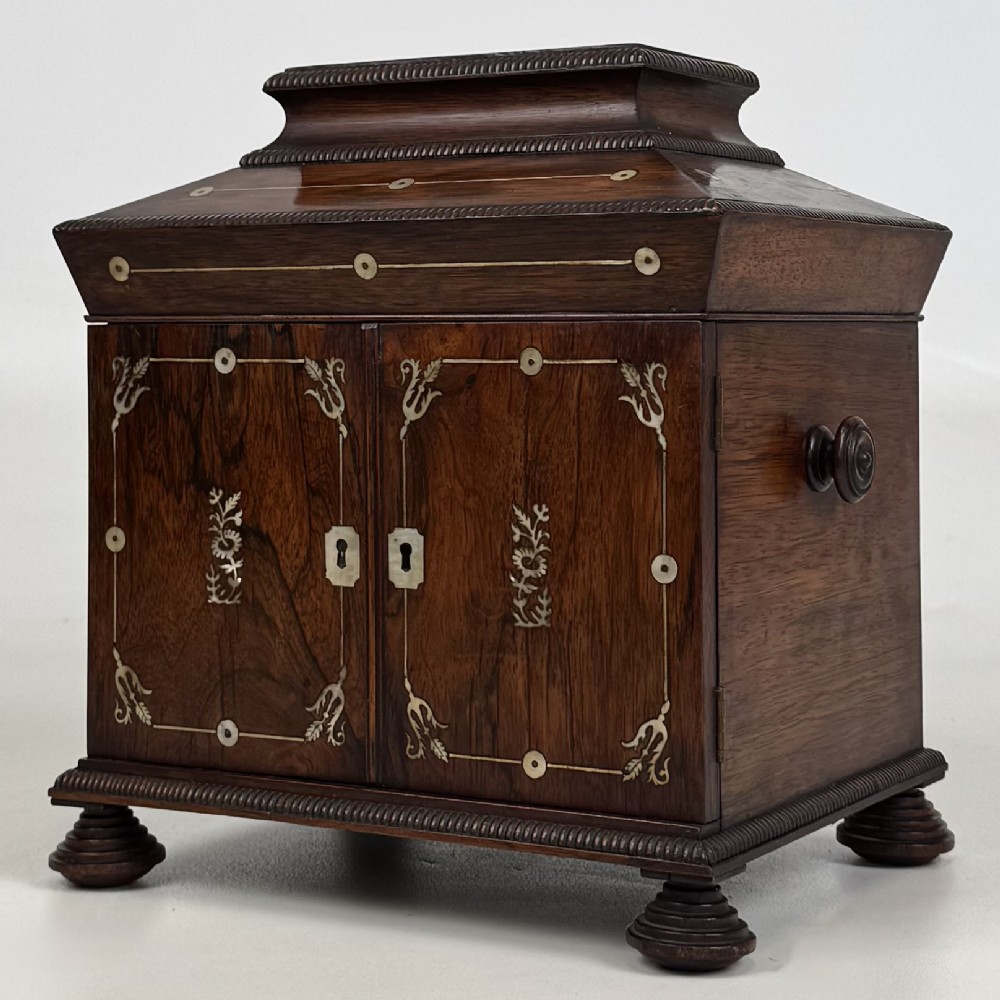 An antique dark rosewood box featuring mother-of-pearl floral inlays, twin front doors, a sarcophagus top, and turned feet. View III