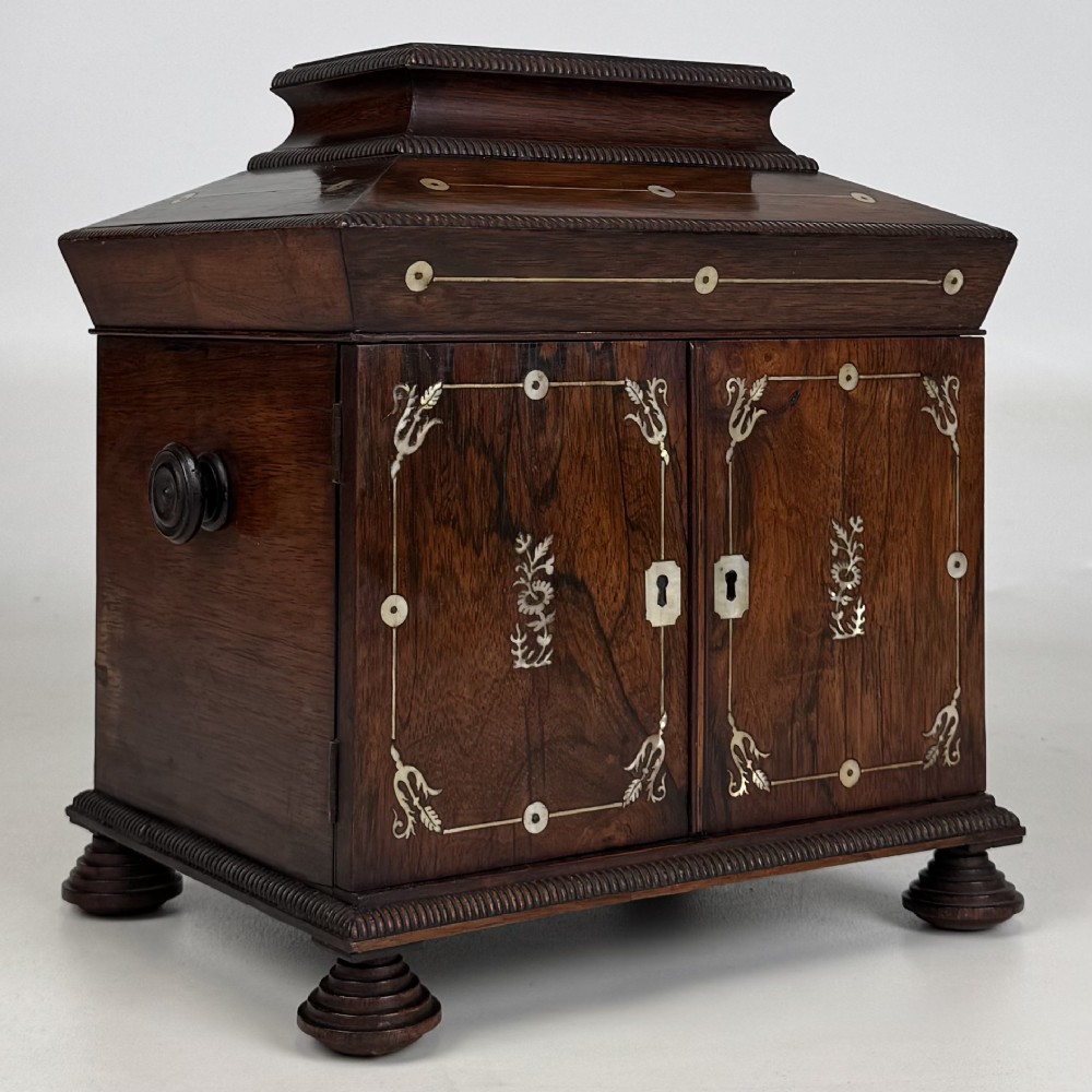 An antique dark rosewood box featuring mother-of-pearl floral inlays, twin front doors, a sarcophagus top, and turned feet. View IX