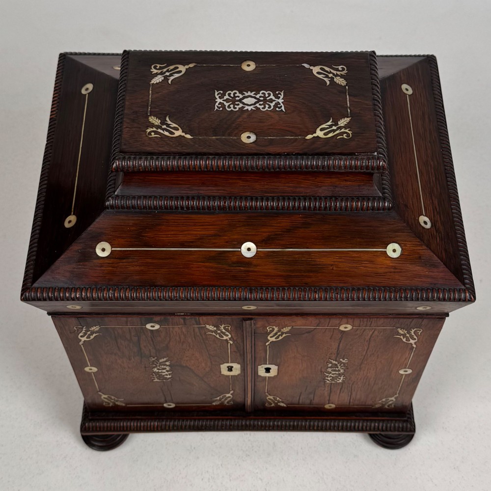 An antique dark rosewood box featuring mother-of-pearl floral inlays, twin front doors, a sarcophagus top, and turned feet. View X