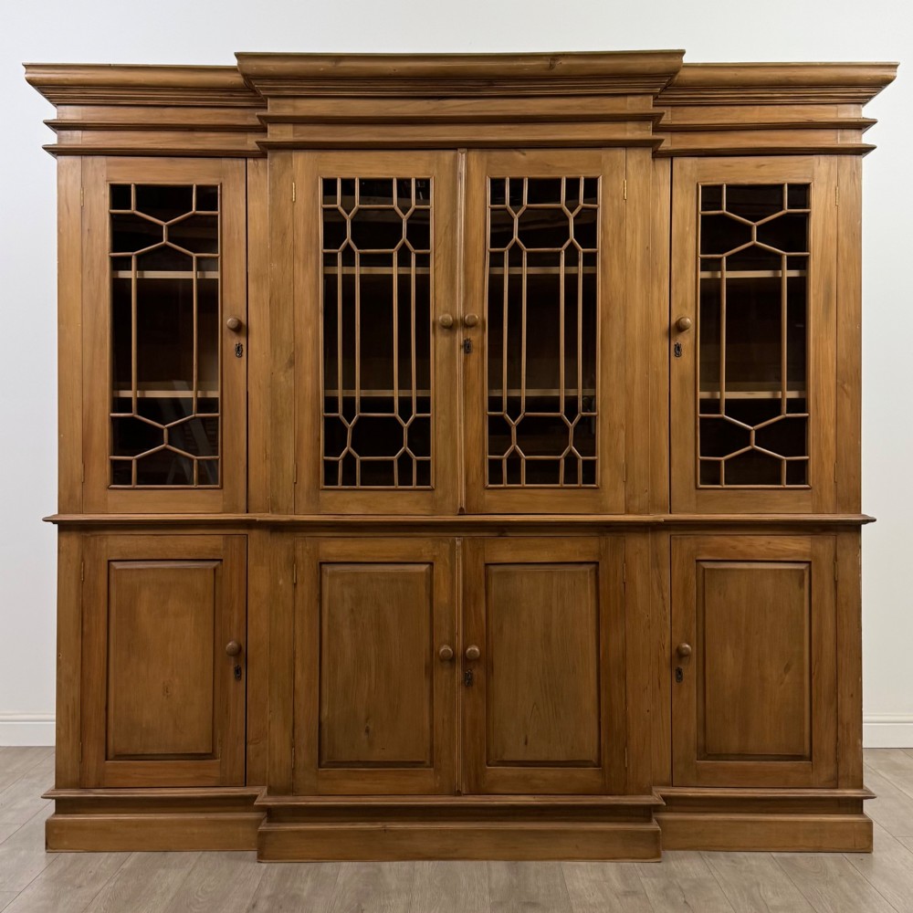 A large 20th-century pine breakfront bookcase featuring upper astragal glazed doors and lower solid panel doors.
