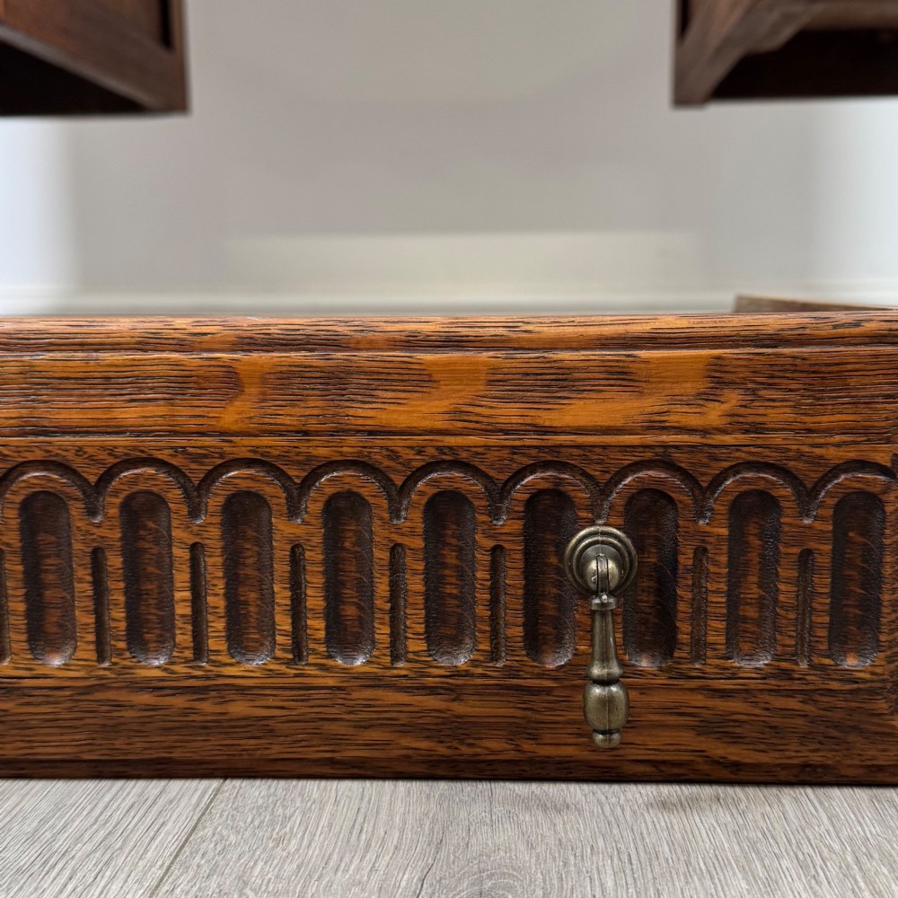 An Edwardian carved oak writing desk featuring five drawers with carved blind arcading, turned legs, stretcher supports, and brass handles. View XI