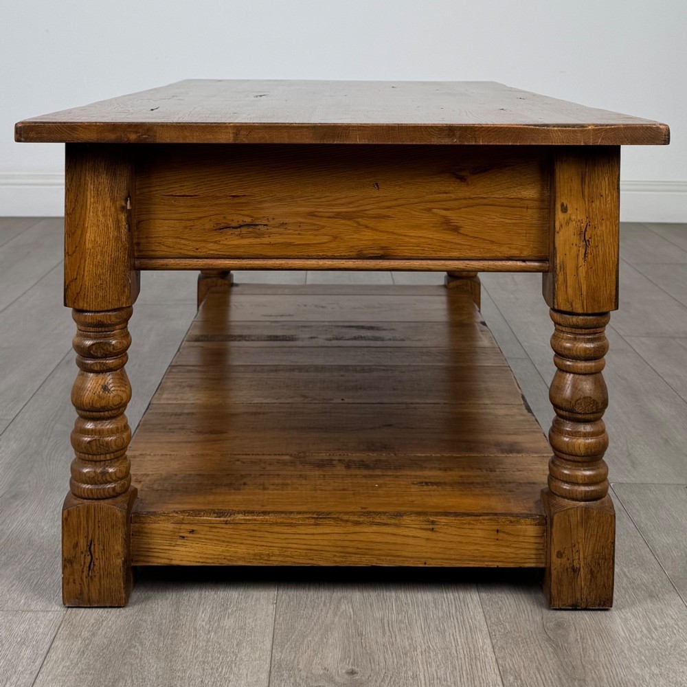 A low rectangular oak coffee table featuring two drawers with metal drop handles, turned legs, and an open lower plank shelf. View VII