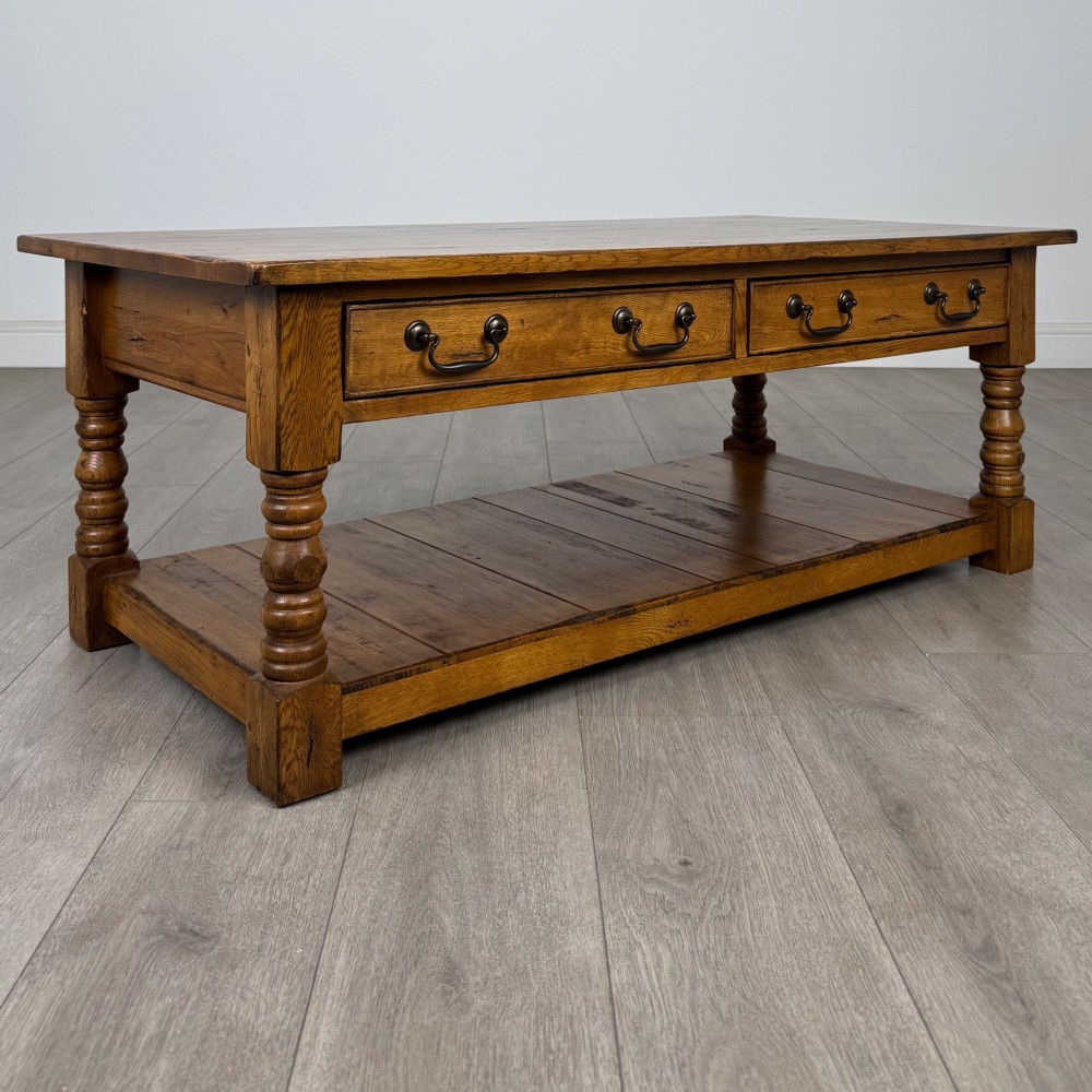 A low rectangular oak coffee table featuring two drawers with metal drop handles, turned legs, and an open lower plank shelf. View VIII