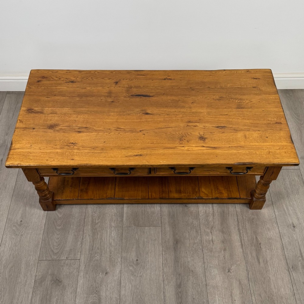A low rectangular oak coffee table featuring two drawers with metal drop handles, turned legs, and an open lower plank shelf. View IX