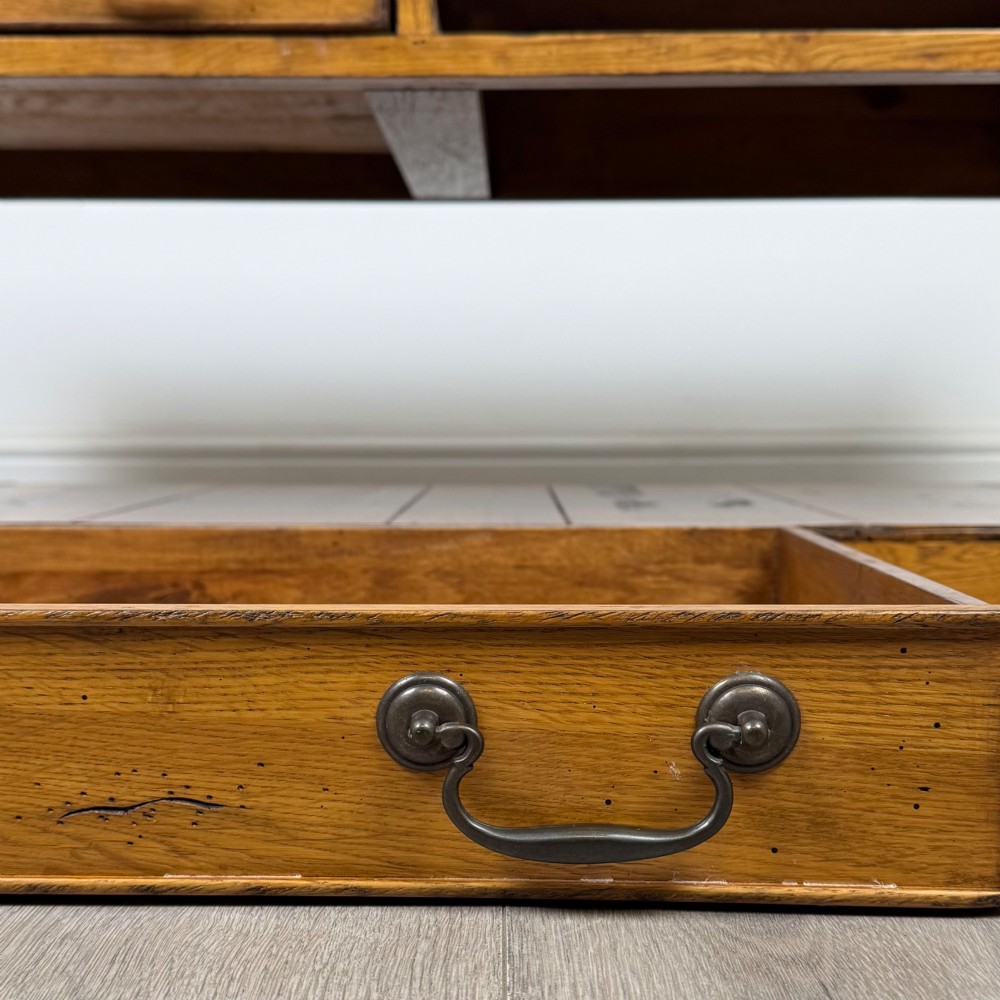 A low rectangular oak coffee table featuring two drawers with metal drop handles, turned legs, and an open lower plank shelf. View XI