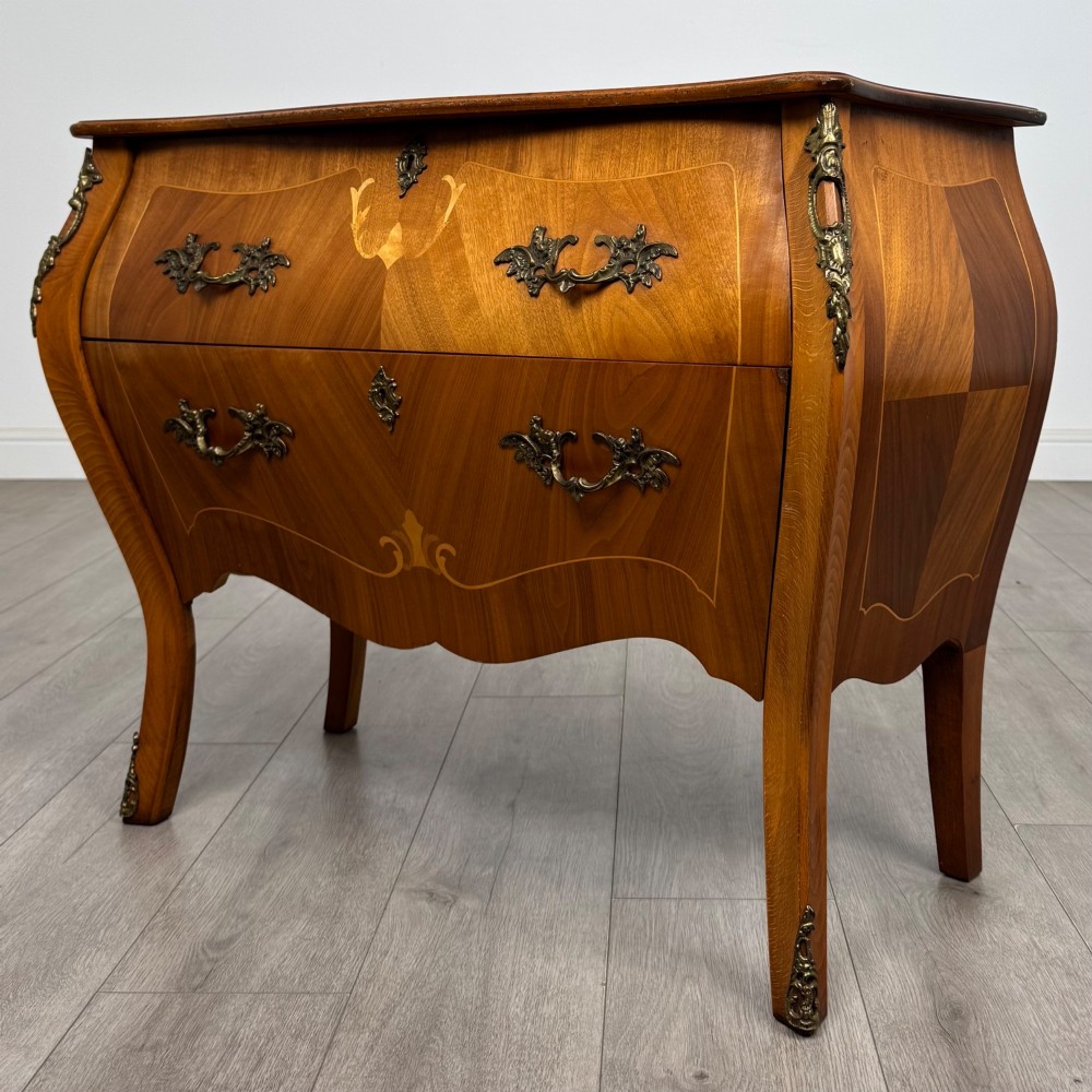 A two-drawer walnut bombe chest featuring curved sides, inlaid marquetry details, cast brass handles, and cabriole legs. View II
