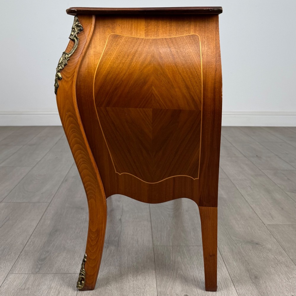 A two-drawer walnut bombe chest featuring curved sides, inlaid marquetry details, cast brass handles, and cabriole legs. View III