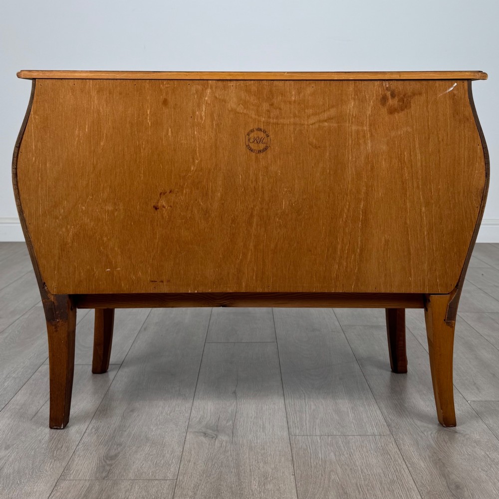 A two-drawer walnut bombe chest featuring curved sides, inlaid marquetry details, cast brass handles, and cabriole legs. View V