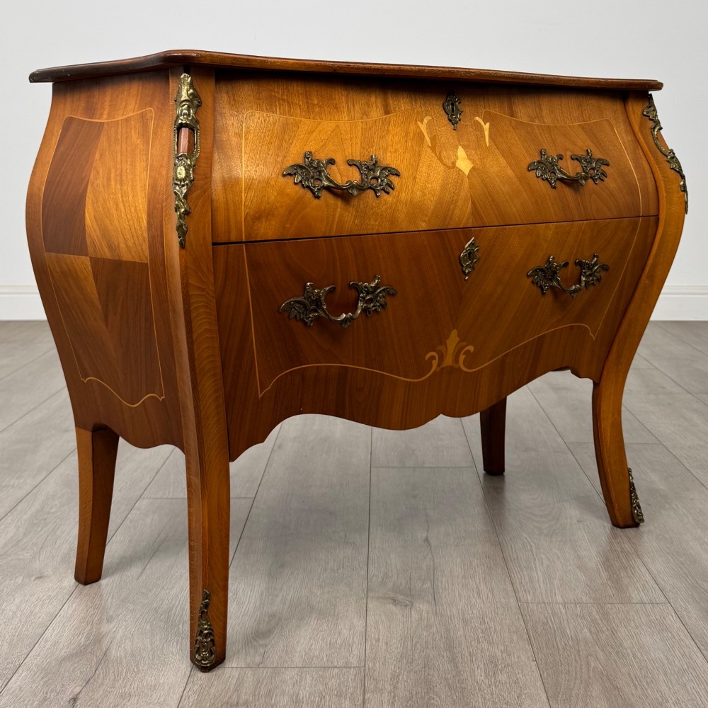 A two-drawer walnut bombe chest featuring curved sides, inlaid marquetry details, cast brass handles, and cabriole legs. View VIII