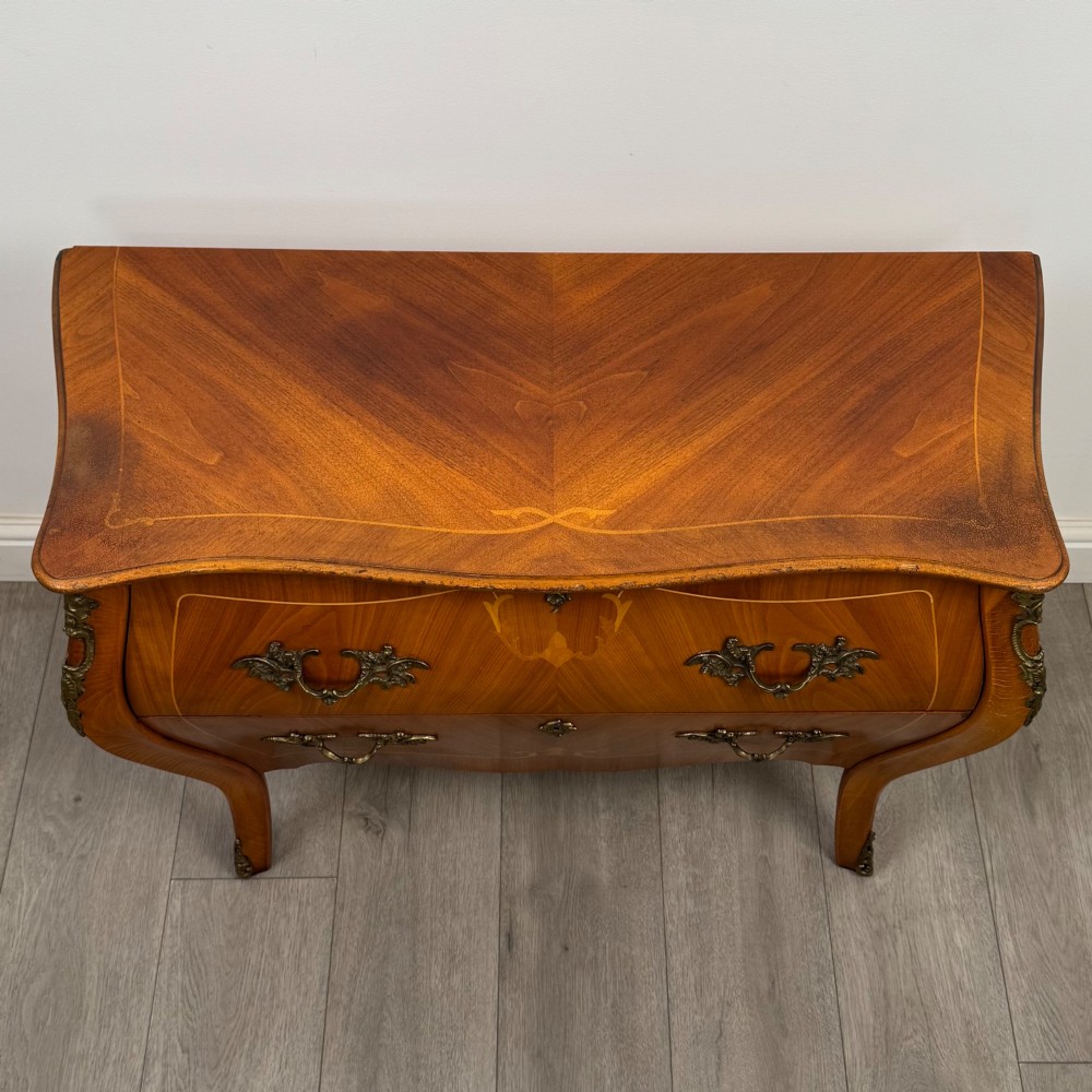 A two-drawer walnut bombe chest featuring curved sides, inlaid marquetry details, cast brass handles, and cabriole legs. View IX