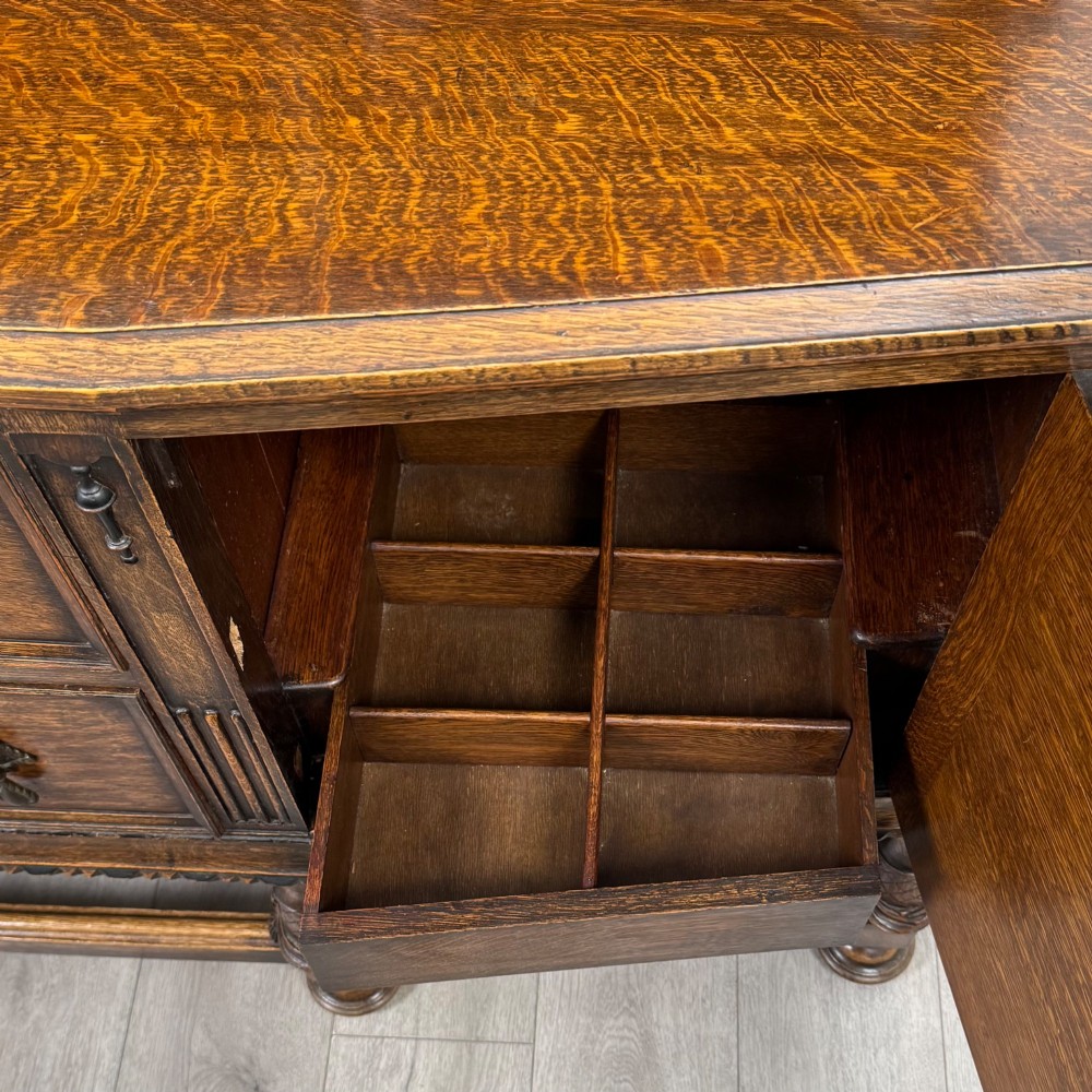 A large 19th-century dark carved oak sideboard featuring a raised upper gallery with carved panels, geometric cupboard doors, central drawers, and turned legs joined by stretchers. View XIII