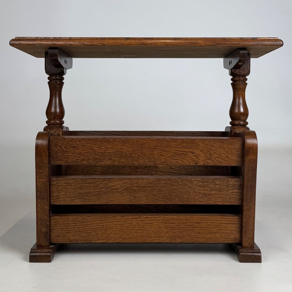 A medium oak side table featuring a flat rectangular tabletop supported by turned baluster posts above a lower slatted storage trough.