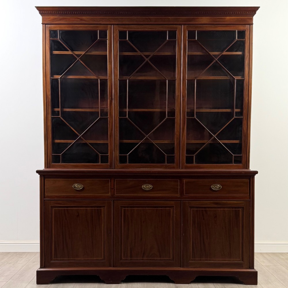 An 18th-century Georgian mahogany bookcase featuring three glazed doors with geometric astragal bars above three drawers and three panelled cupboard doors.