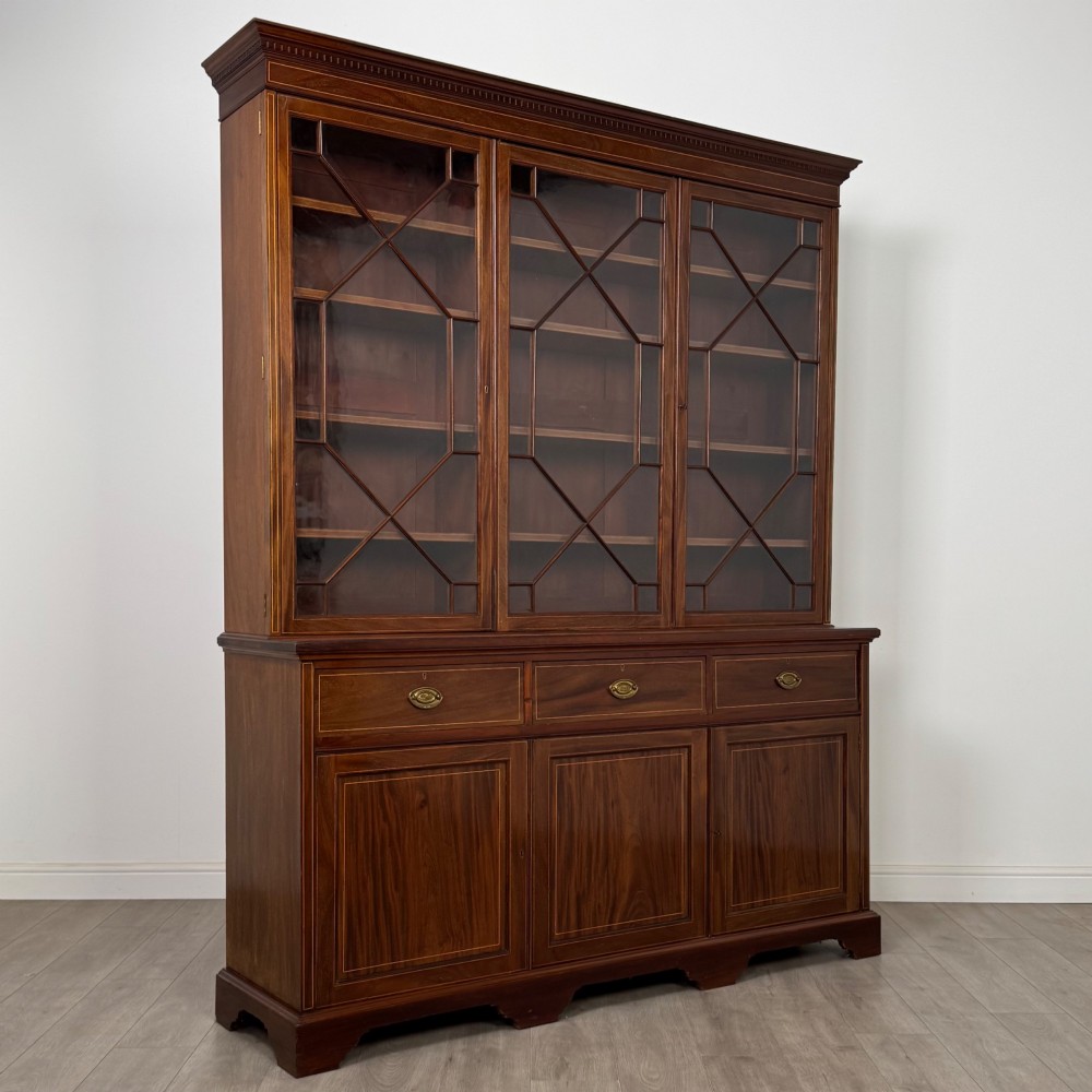 An 18th-century Georgian mahogany bookcase featuring three glazed doors with geometric astragal bars above three drawers and three panelled cupboard doors. View IX