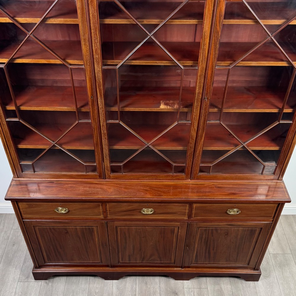 An 18th-century Georgian mahogany bookcase featuring three glazed doors with geometric astragal bars above three drawers and three panelled cupboard doors. View X