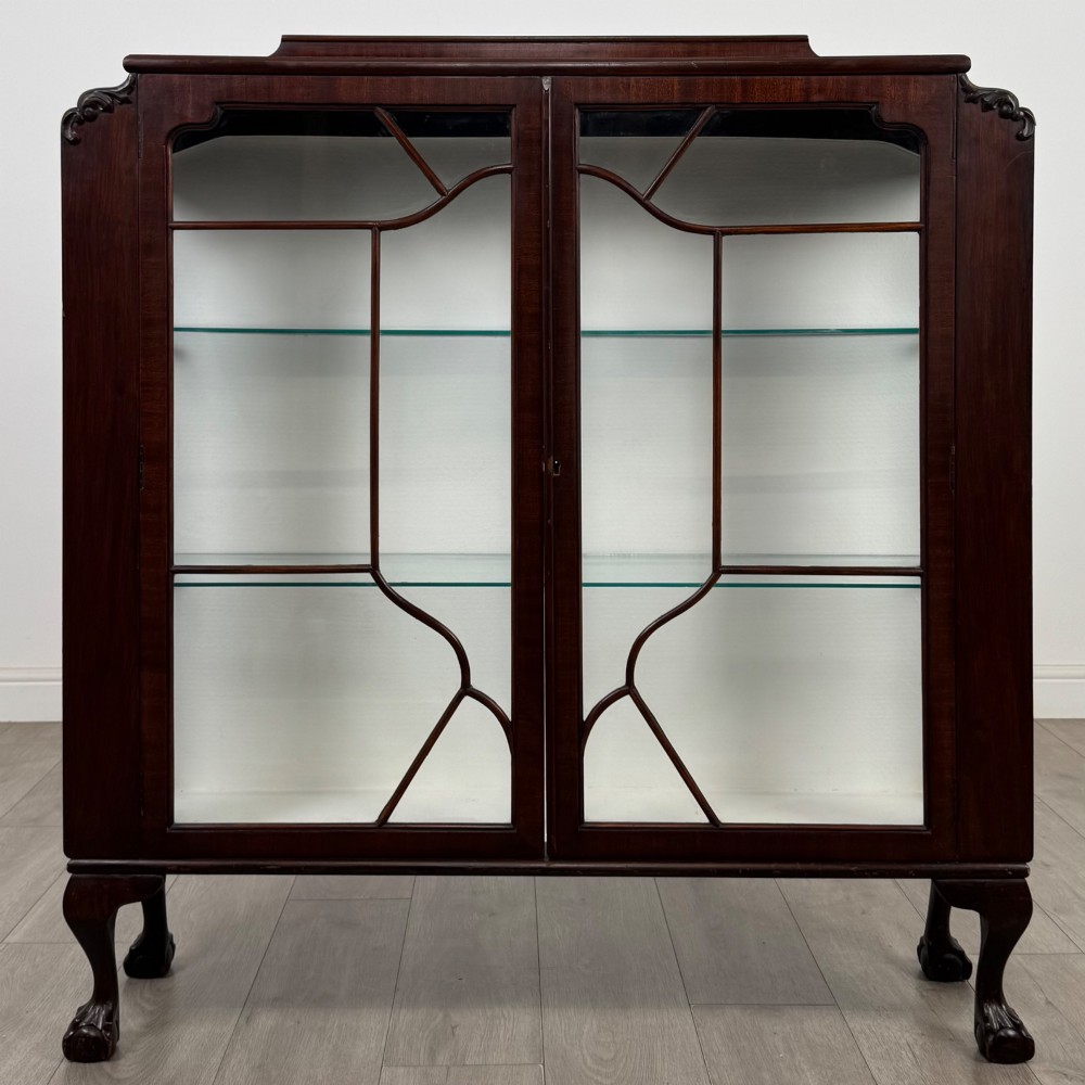 An Edwardian mahogany display cabinet featuring twin astragal glazed doors, glass interior shelves, and cabriole legs with ball and claw feet.