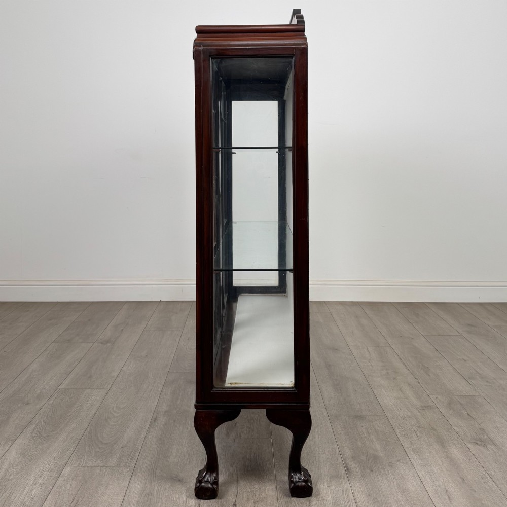 An Edwardian mahogany display cabinet featuring twin astragal glazed doors, glass interior shelves, and cabriole legs with ball and claw feet. View IV