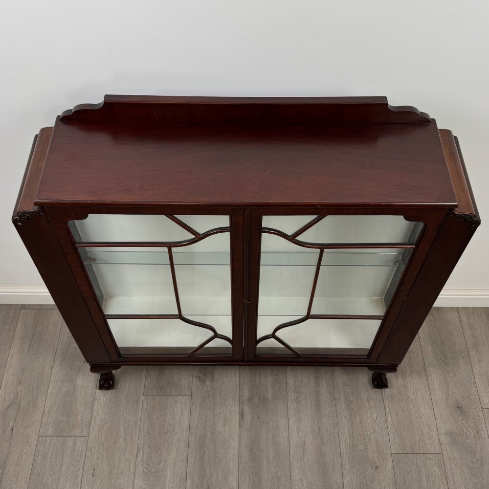 An Edwardian mahogany display cabinet featuring twin astragal glazed doors, glass interior shelves, and cabriole legs with ball and claw feet. View X