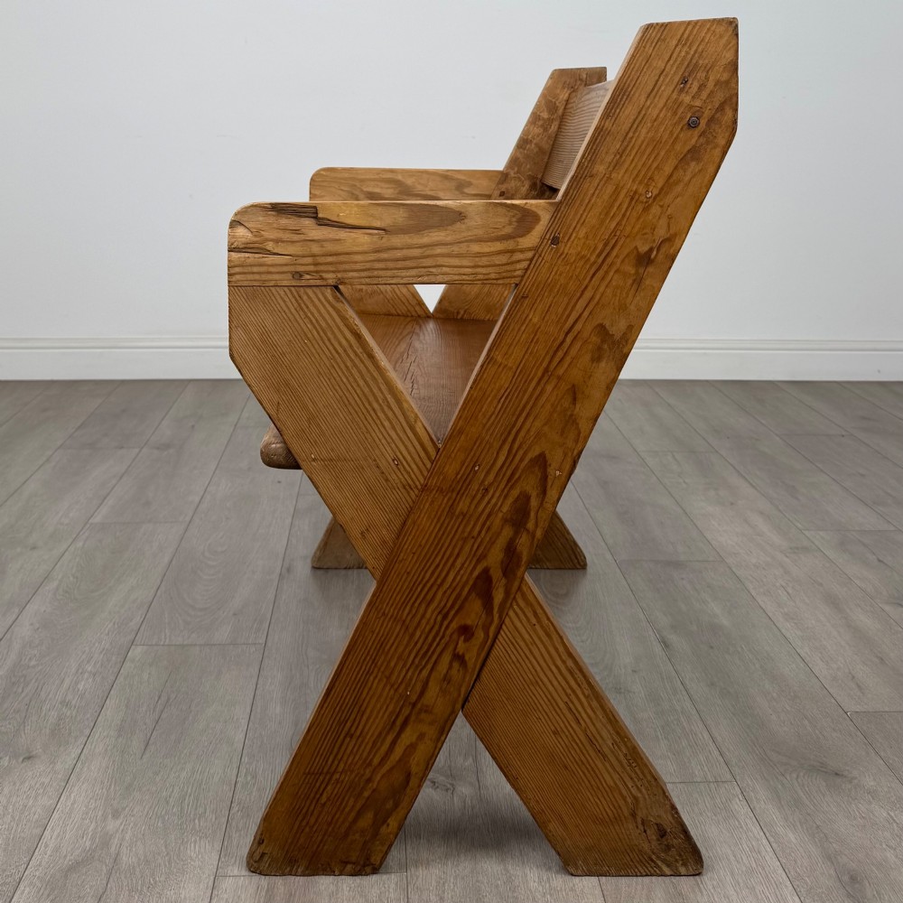 A nineteenth-century pitch pine bench featuring an X-frame structure, integrated side armrests, and a single horizontal back rail. View II
