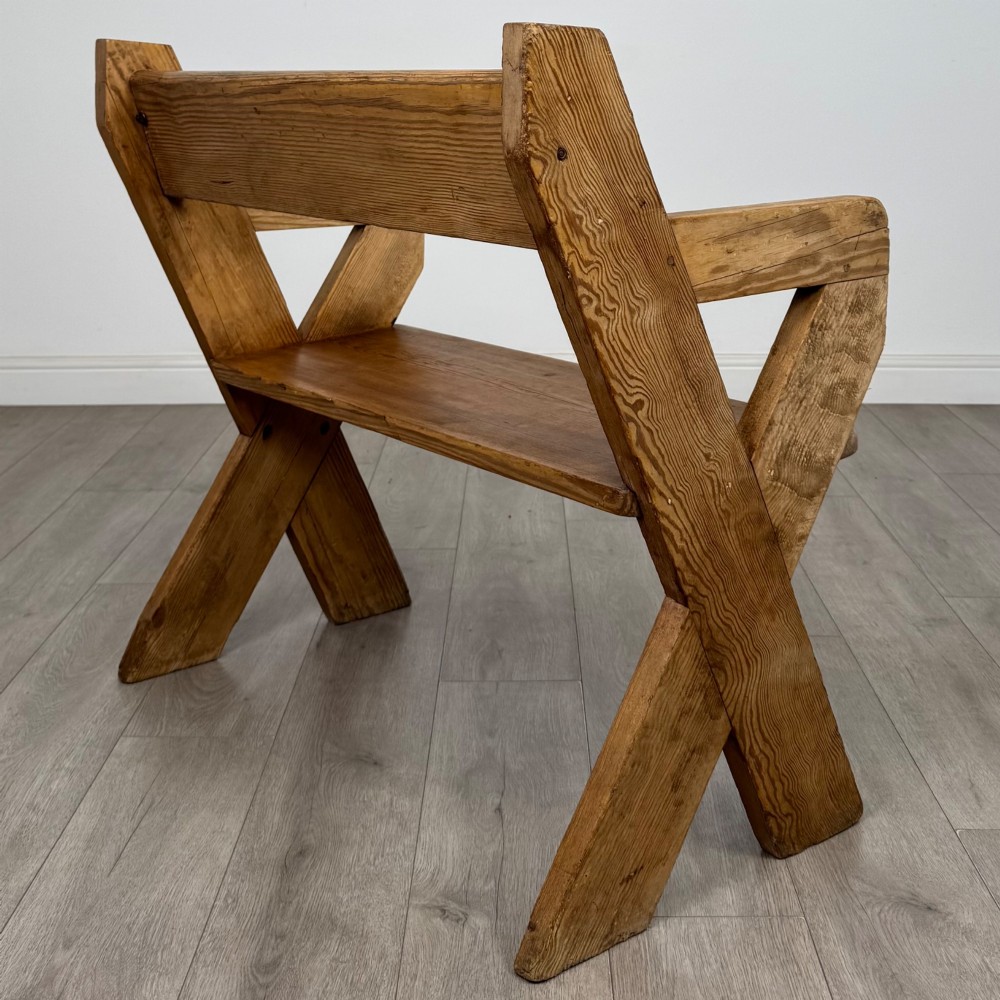 A nineteenth-century pitch pine bench featuring an X-frame structure, integrated side armrests, and a single horizontal back rail. View V