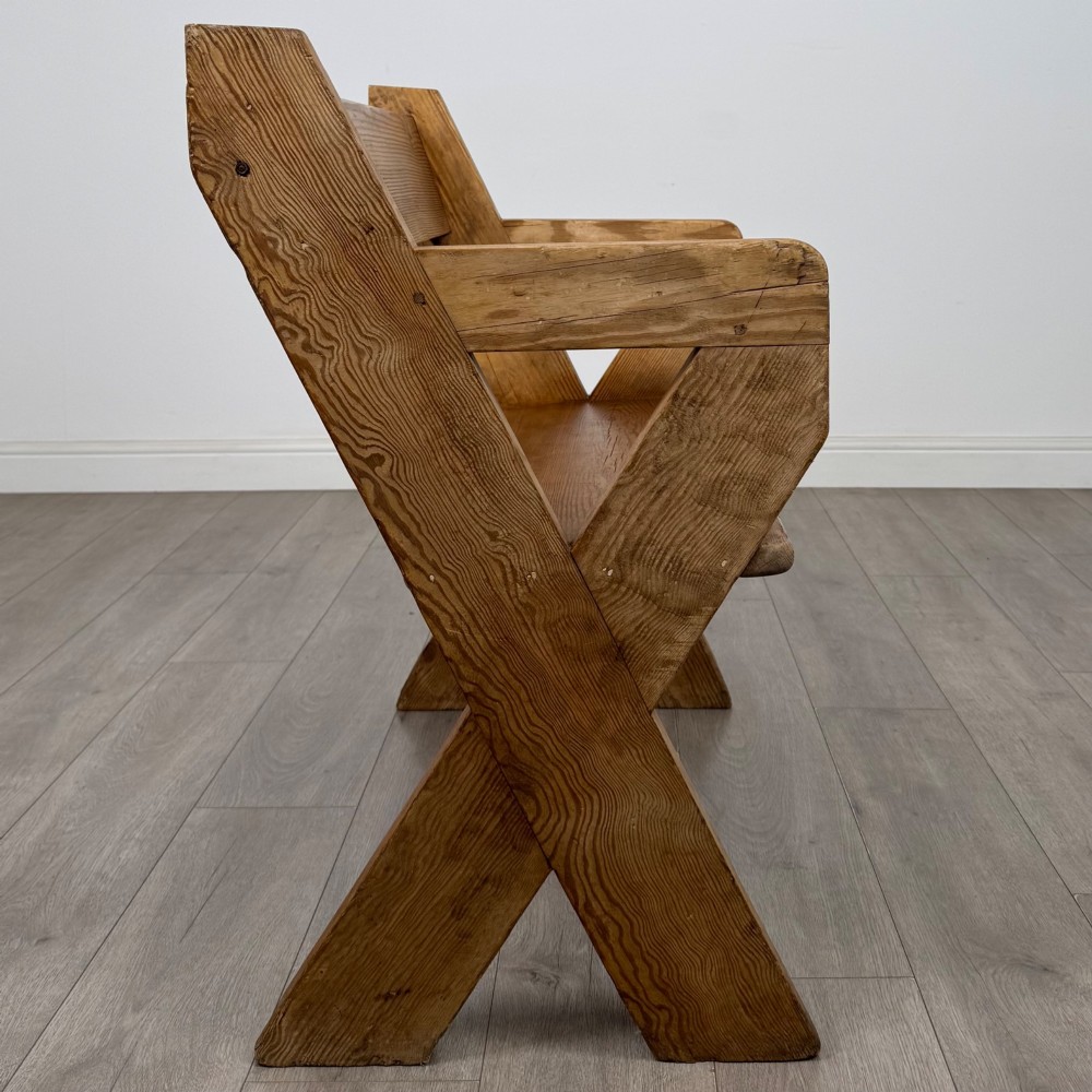 A nineteenth-century pitch pine bench featuring an X-frame structure, integrated side armrests, and a single horizontal back rail. View VI