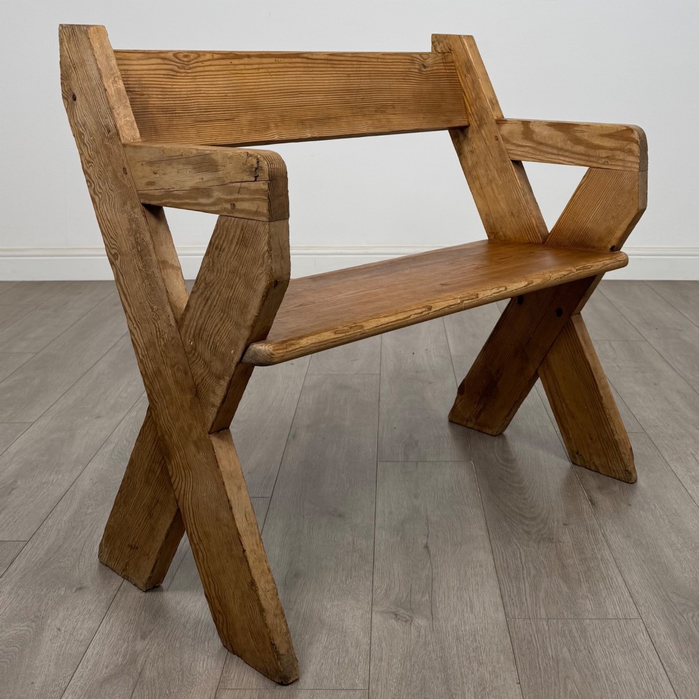 A nineteenth-century pitch pine bench featuring an X-frame structure, integrated side armrests, and a single horizontal back rail. View VII