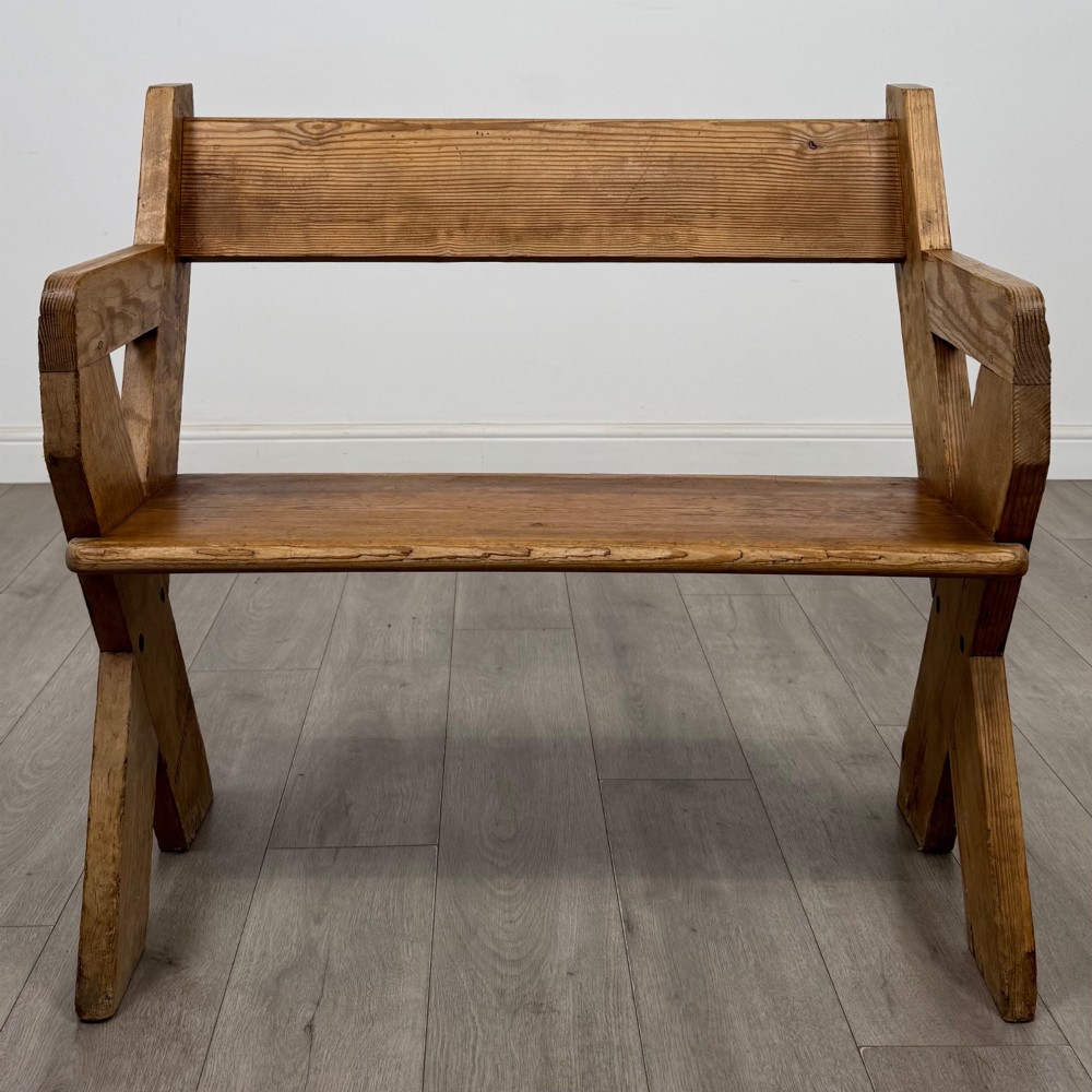 A nineteenth-century pitch pine bench featuring an X-frame structure, integrated side armrests, and a single horizontal back rail. View VIII