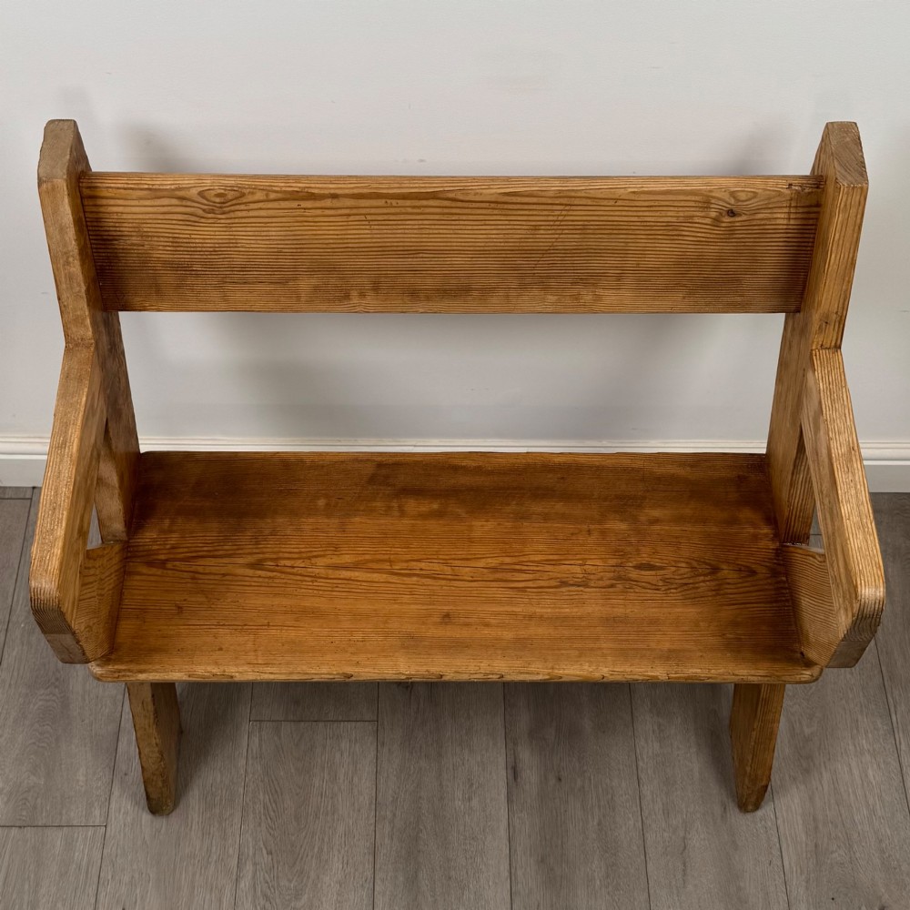 A nineteenth-century pitch pine bench featuring an X-frame structure, integrated side armrests, and a single horizontal back rail. View IX
