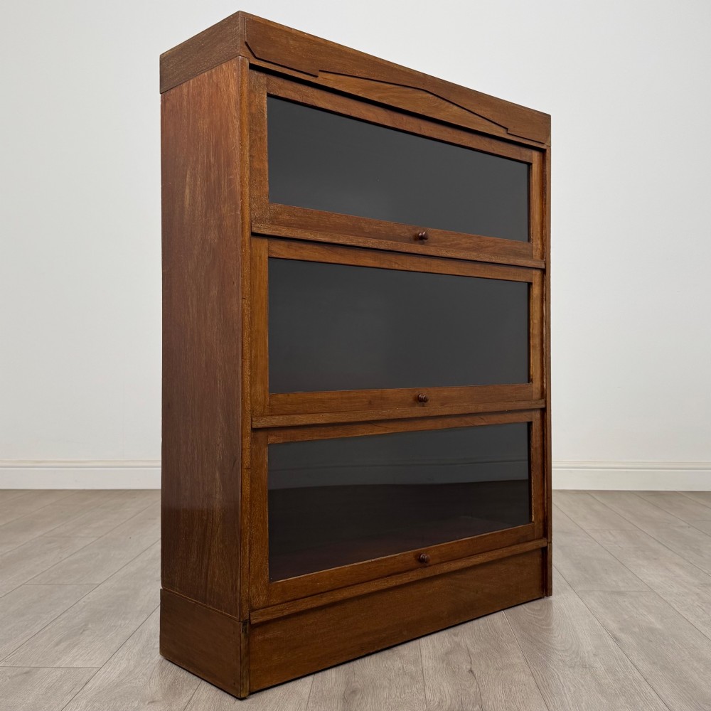 A three-tier mahogany sectional bookcase featuring lift-up glazed doors with small wooden knobs. View IX