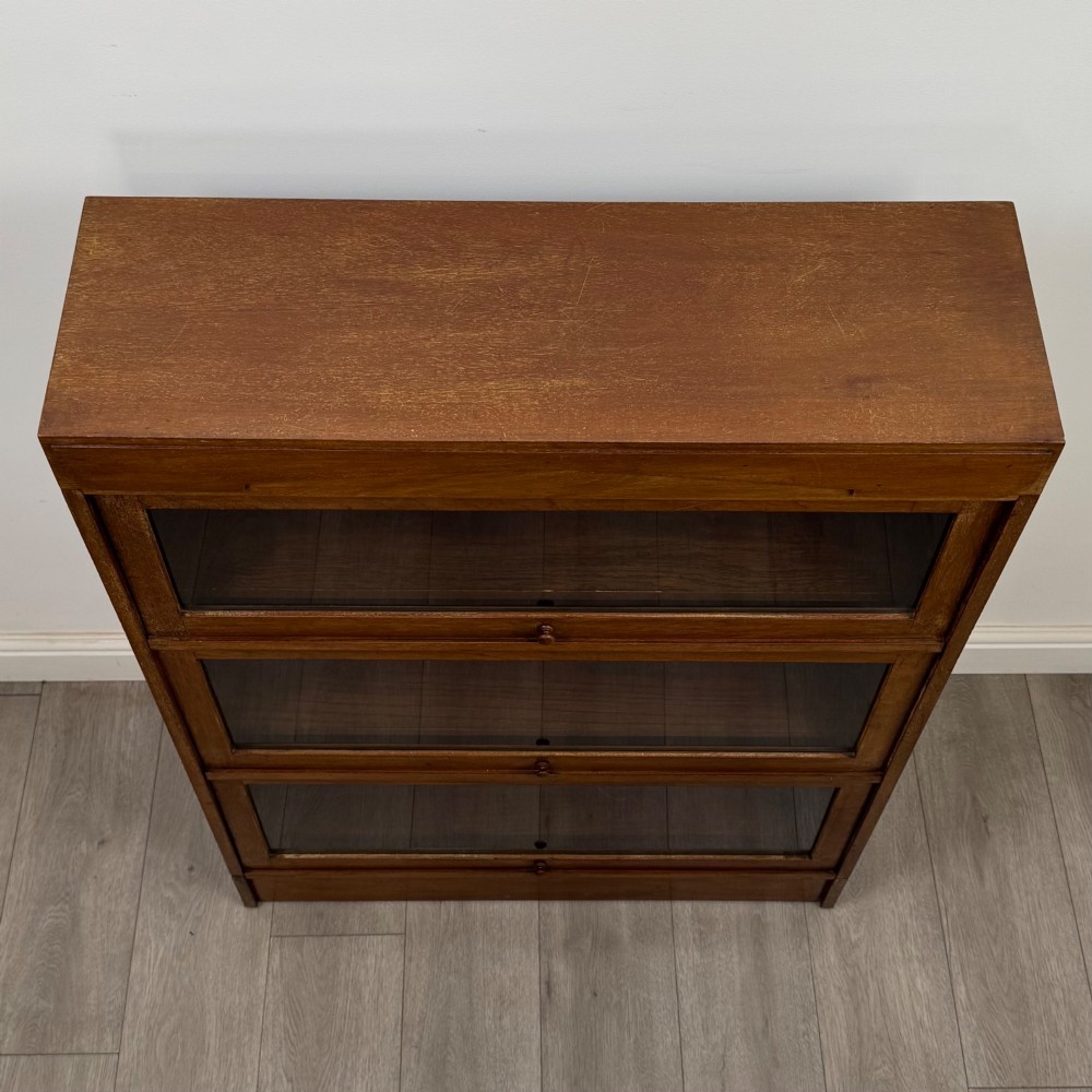 A three-tier mahogany sectional bookcase featuring lift-up glazed doors with small wooden knobs. View X