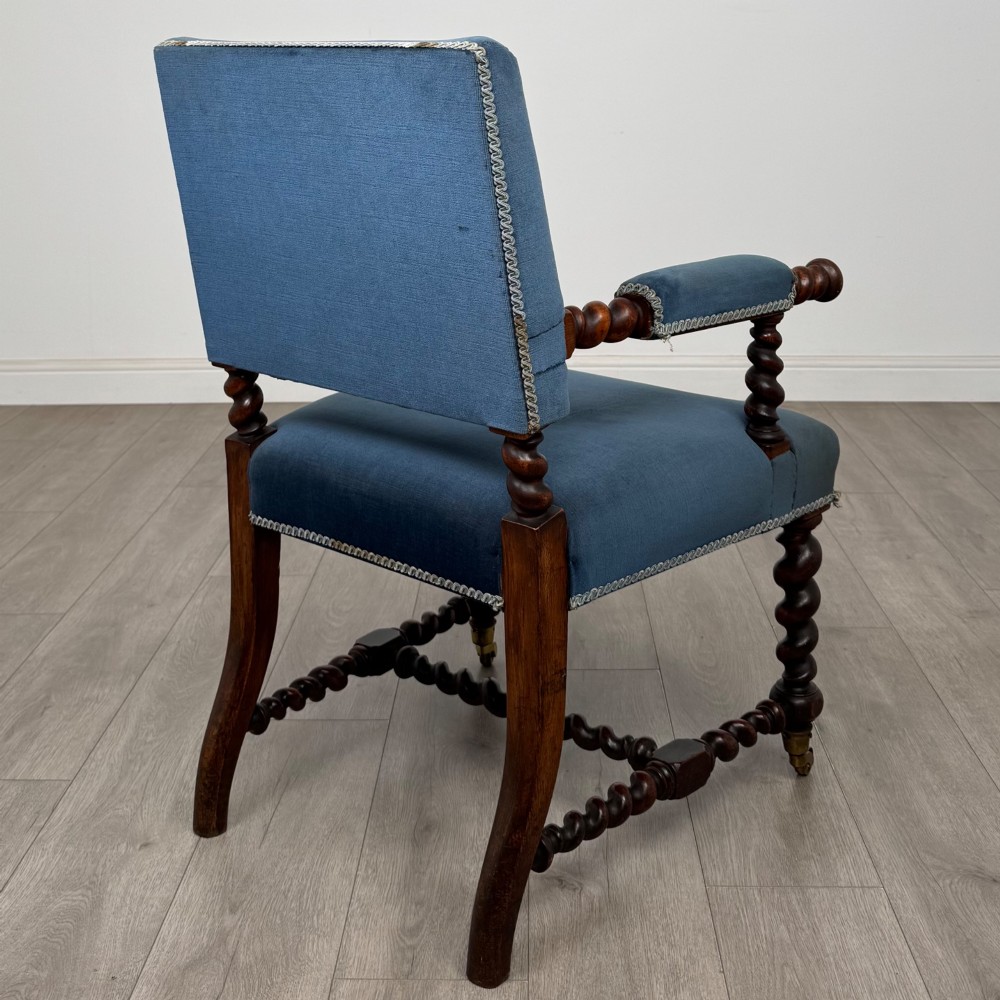 A nineteenth-century dark oak armchair featuring barley twist legs and stretchers, blue fabric upholstery, and brass front castors. View V