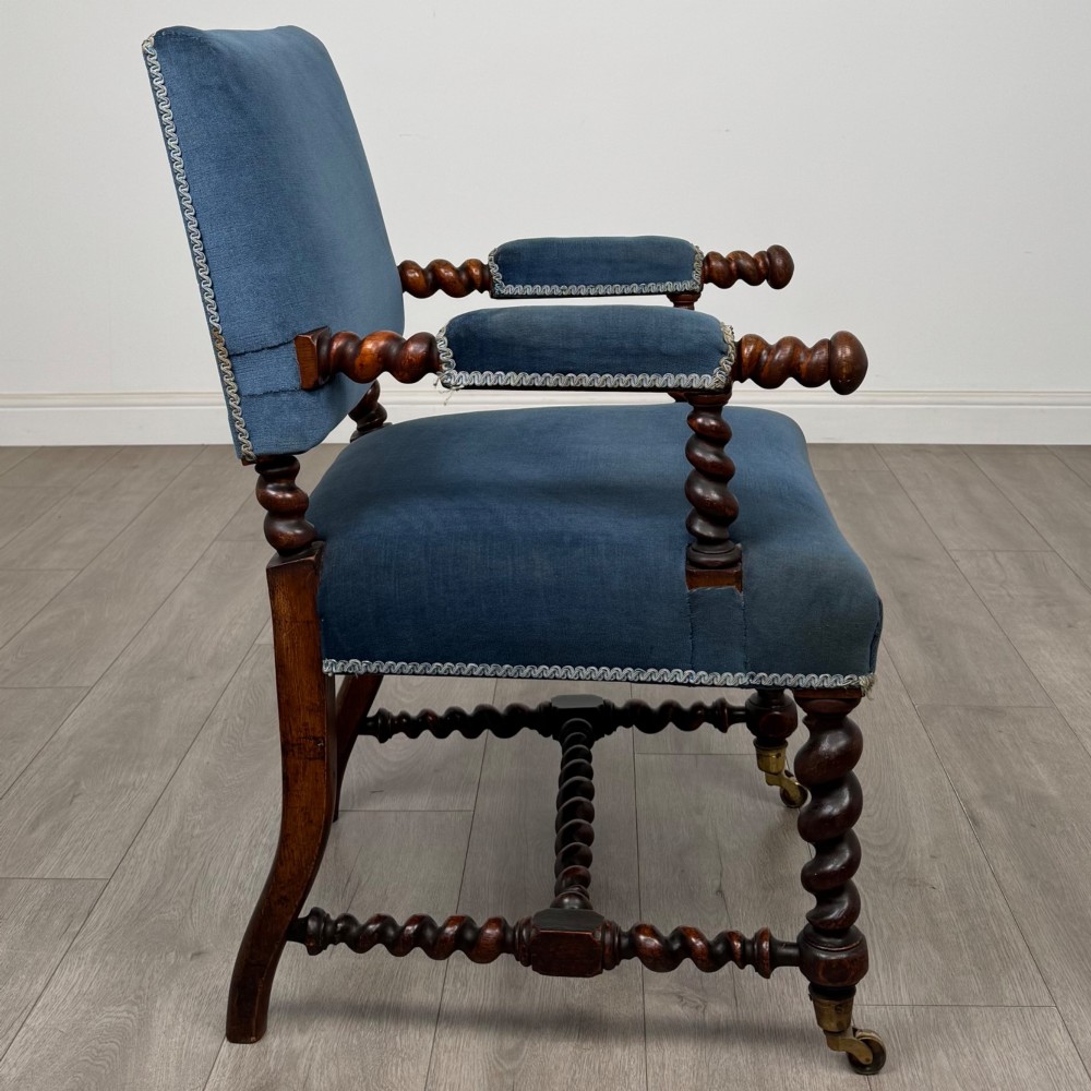 A nineteenth-century dark oak armchair featuring barley twist legs and stretchers, blue fabric upholstery, and brass front castors. View VI