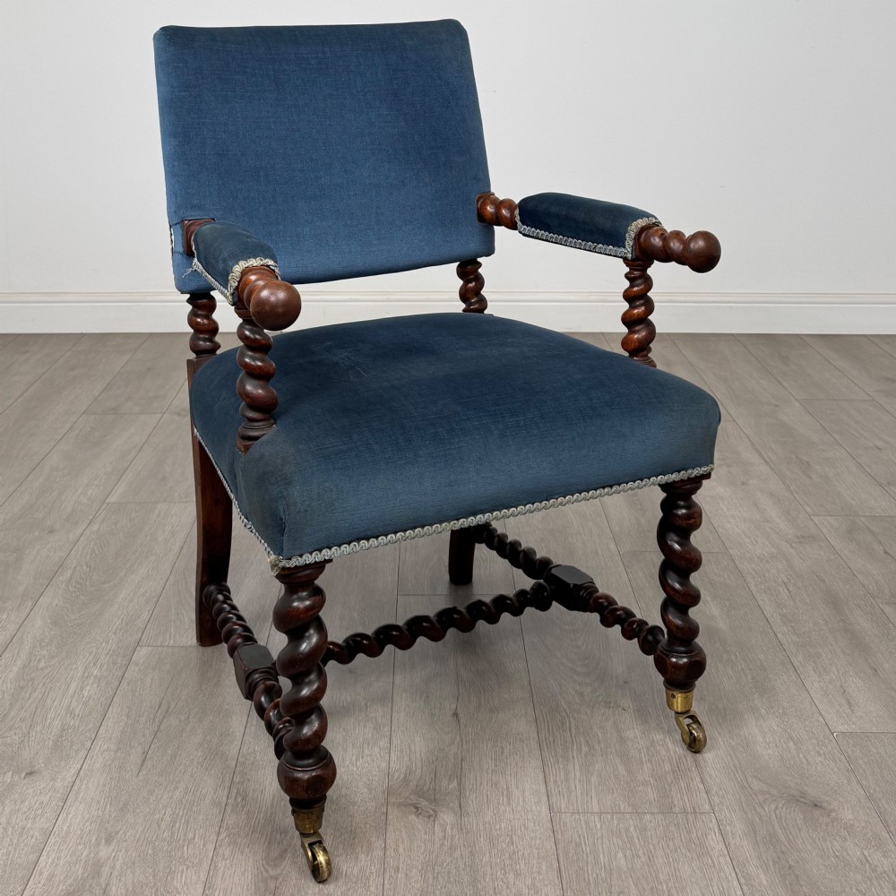 A nineteenth-century dark oak armchair featuring barley twist legs and stretchers, blue fabric upholstery, and brass front castors. View VII