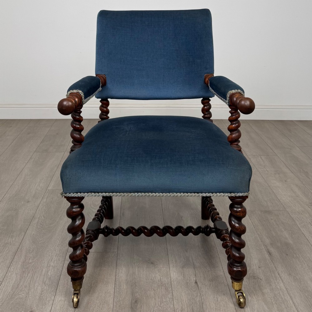 A nineteenth-century dark oak armchair featuring barley twist legs and stretchers, blue fabric upholstery, and brass front castors. View VIII