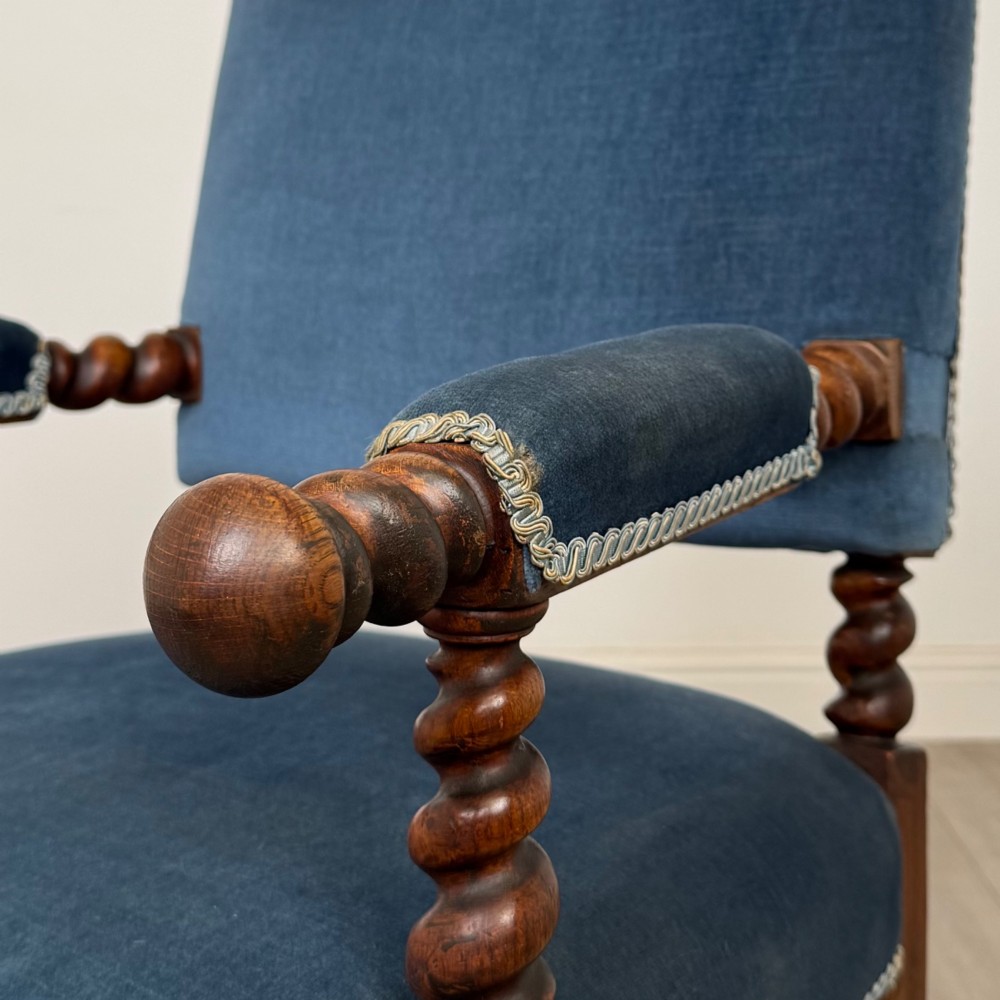 A nineteenth-century dark oak armchair featuring barley twist legs and stretchers, blue fabric upholstery, and brass front castors. View X