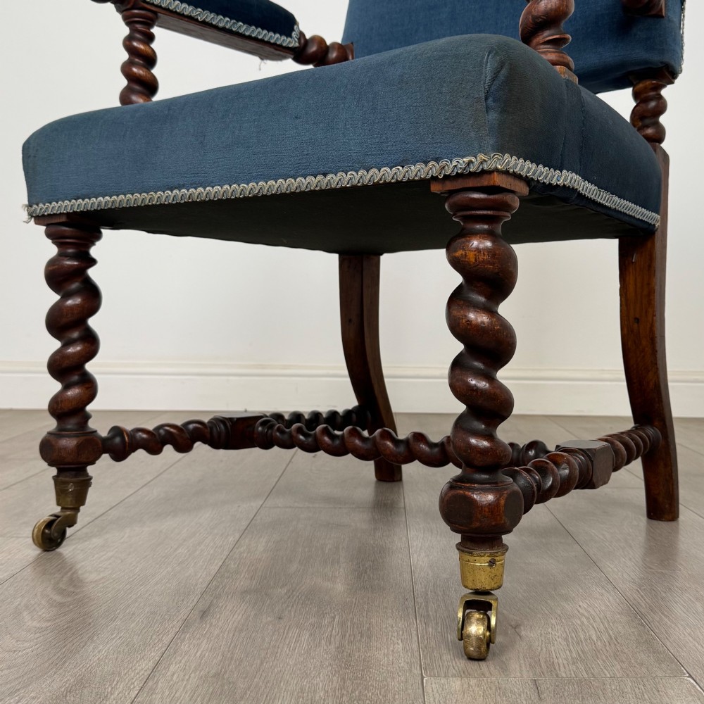 A nineteenth-century dark oak armchair featuring barley twist legs and stretchers, blue fabric upholstery, and brass front castors. View XI