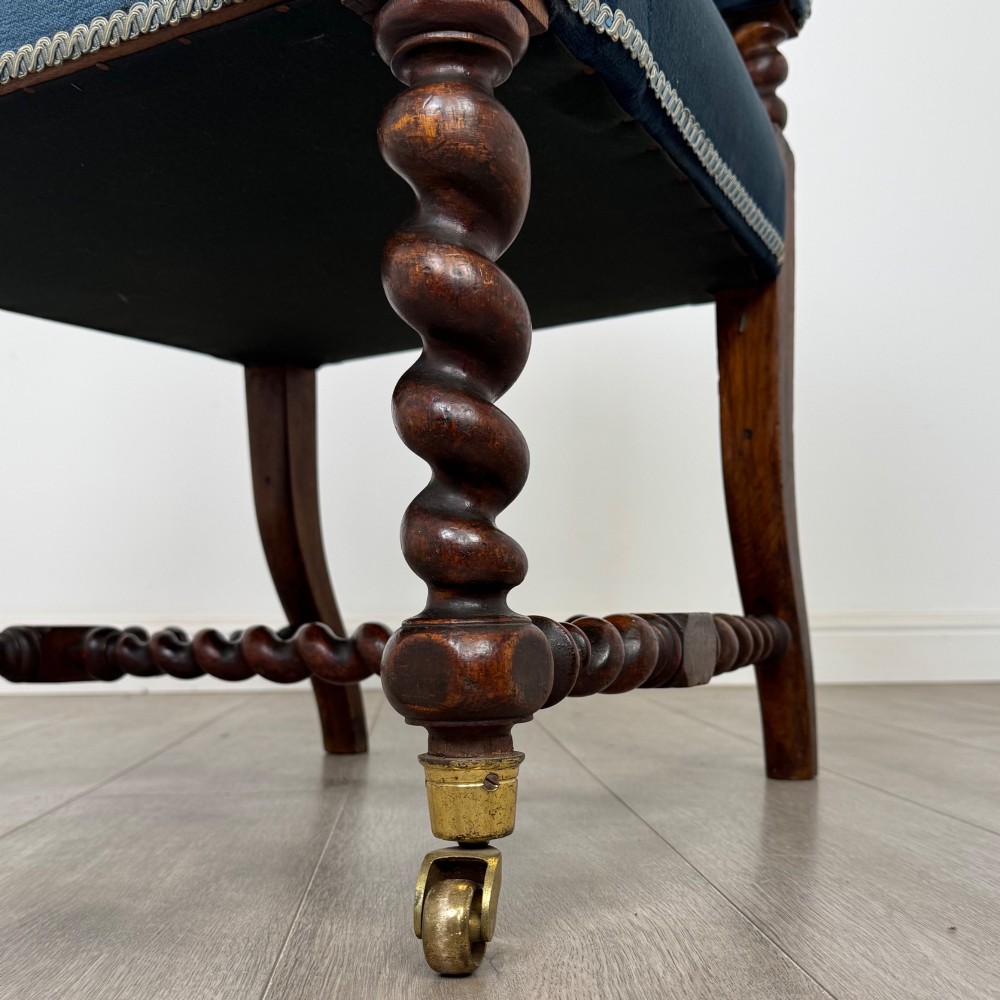 A nineteenth-century dark oak armchair featuring barley twist legs and stretchers, blue fabric upholstery, and brass front castors. View XII
