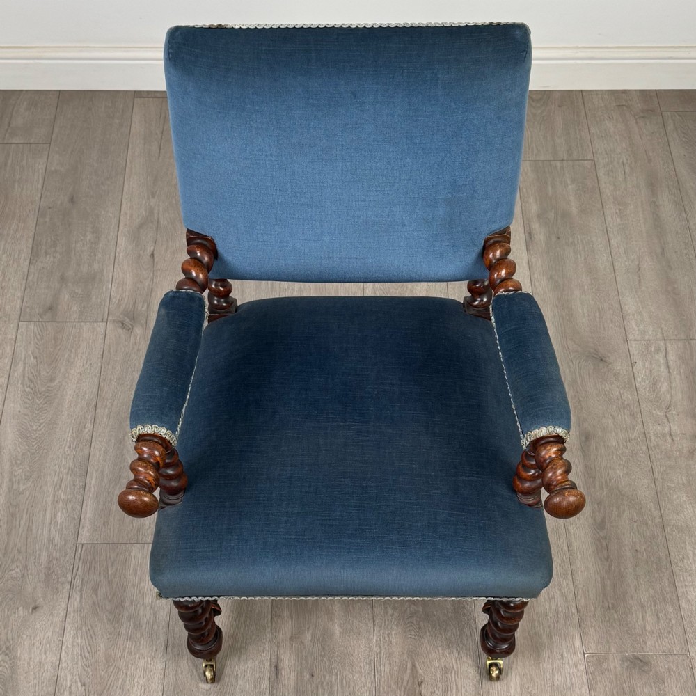 A nineteenth-century dark oak armchair featuring barley twist legs and stretchers, blue fabric upholstery, and brass front castors. View XIII