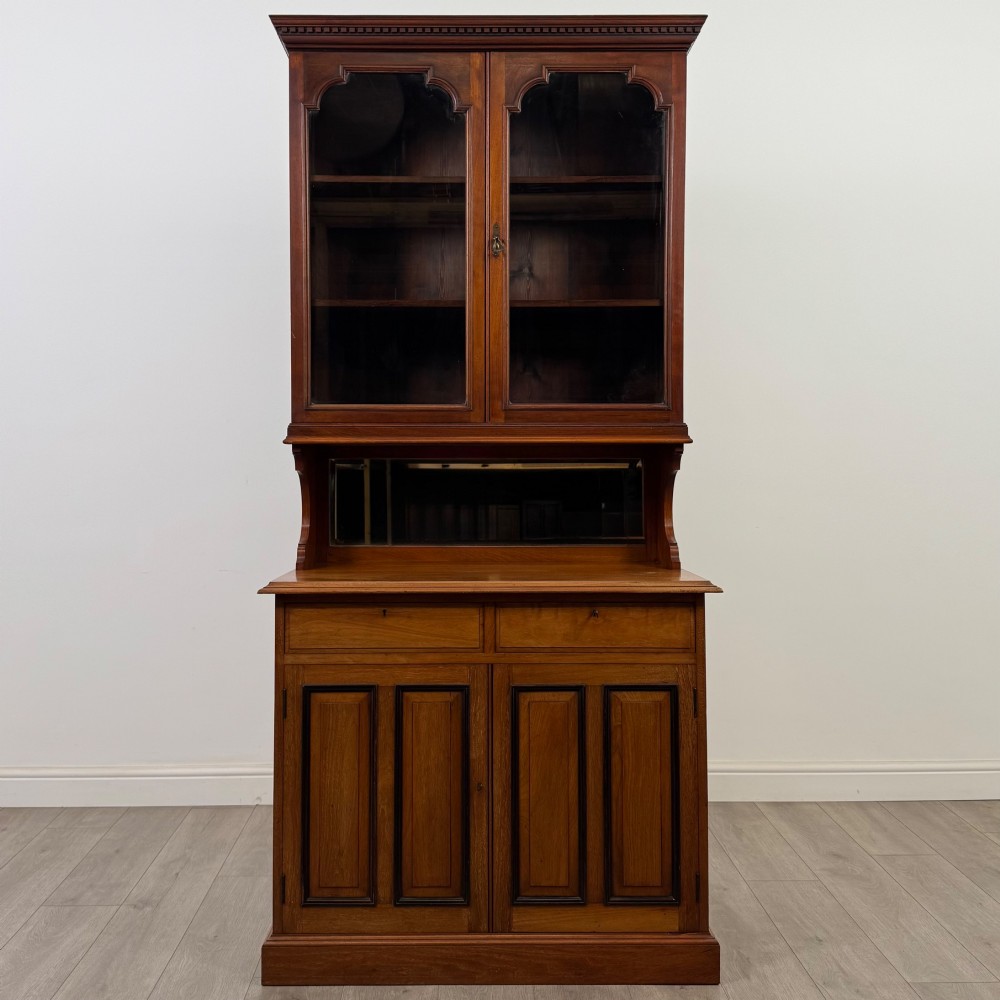 An Edwardian walnut bookcase featuring a two-door glazed upper section with arched frames, a central mirrored niche, and a base cabinet with drawers and panelled doors. View II