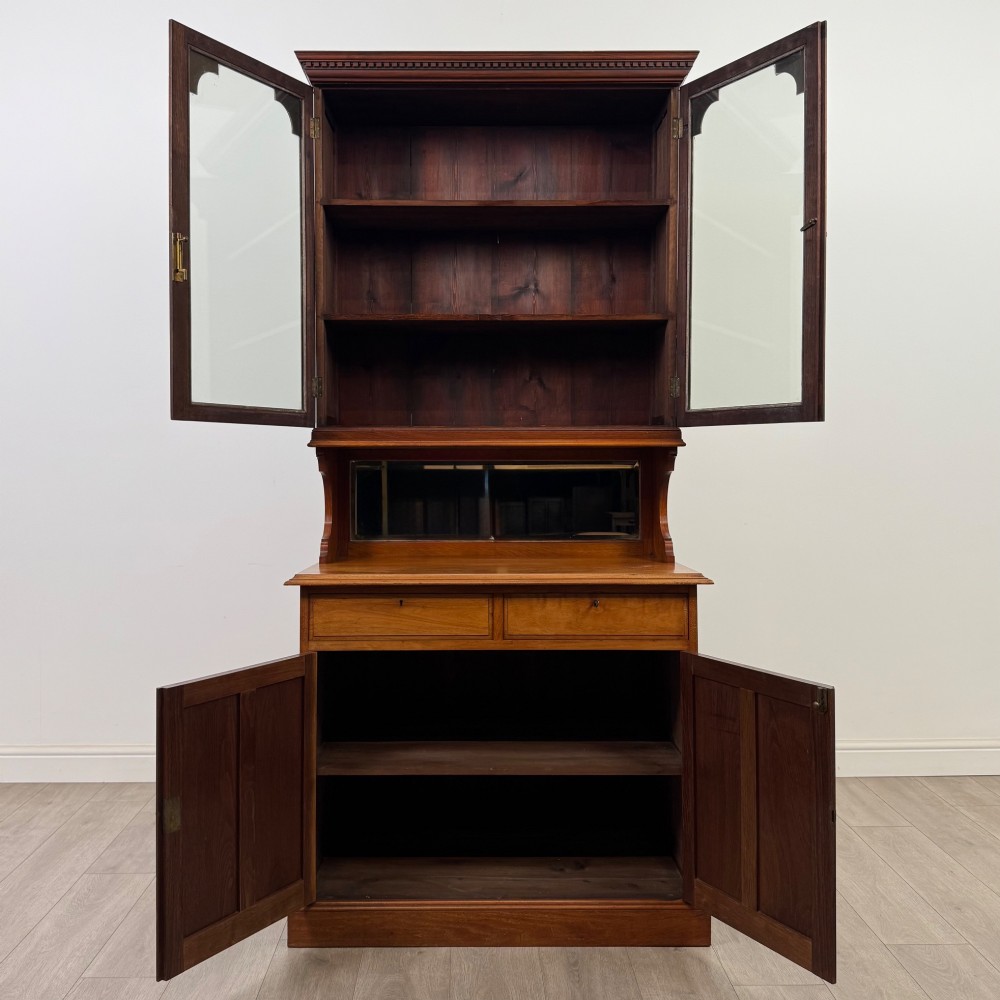 An Edwardian walnut bookcase featuring a two-door glazed upper section with arched frames, a central mirrored niche, and a base cabinet with drawers and panelled doors. View III