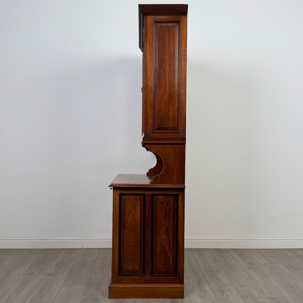 An Edwardian walnut bookcase featuring a two-door glazed upper section with arched frames, a central mirrored niche, and a base cabinet with drawers and panelled doors. View V