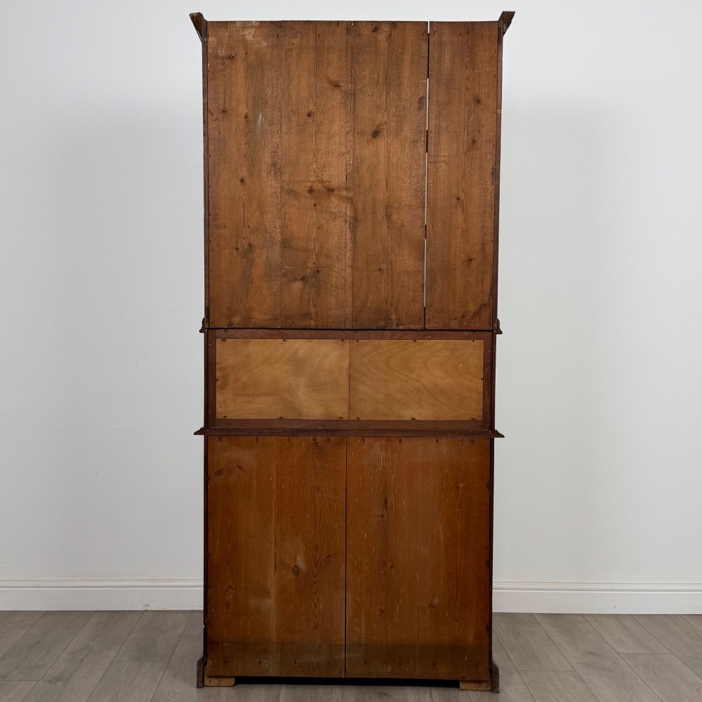 An Edwardian walnut bookcase featuring a two-door glazed upper section with arched frames, a central mirrored niche, and a base cabinet with drawers and panelled doors. View VII