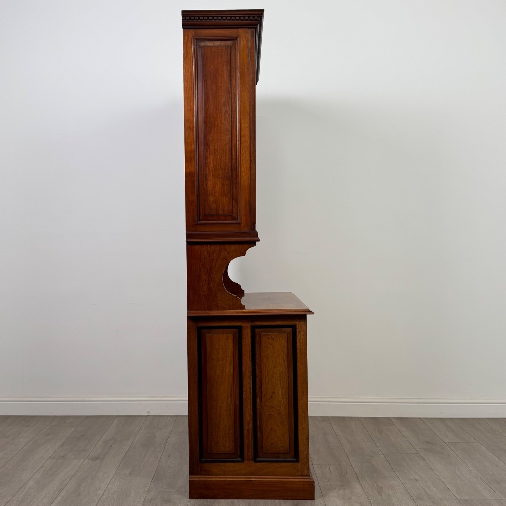An Edwardian walnut bookcase featuring a two-door glazed upper section with arched frames, a central mirrored niche, and a base cabinet with drawers and panelled doors. View IX