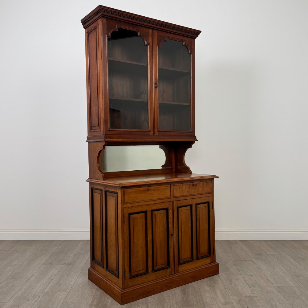 An Edwardian walnut bookcase featuring a two-door glazed upper section with arched frames, a central mirrored niche, and a base cabinet with drawers and panelled doors. View X