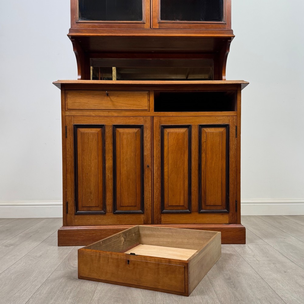 An Edwardian walnut bookcase featuring a two-door glazed upper section with arched frames, a central mirrored niche, and a base cabinet with drawers and panelled doors. View XII