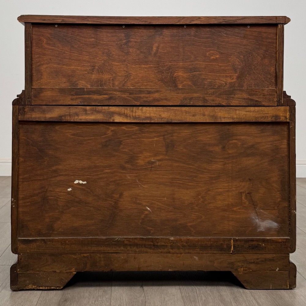 A dark carved oak chest of drawers featuring three drawers, floral relief carvings, and brass pendant handles set on carved bracket feet. View IV