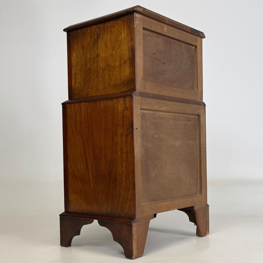 A small dark mahogany chest of drawers with five stacked drawers, brass ring handles, and bracket feet. View IV