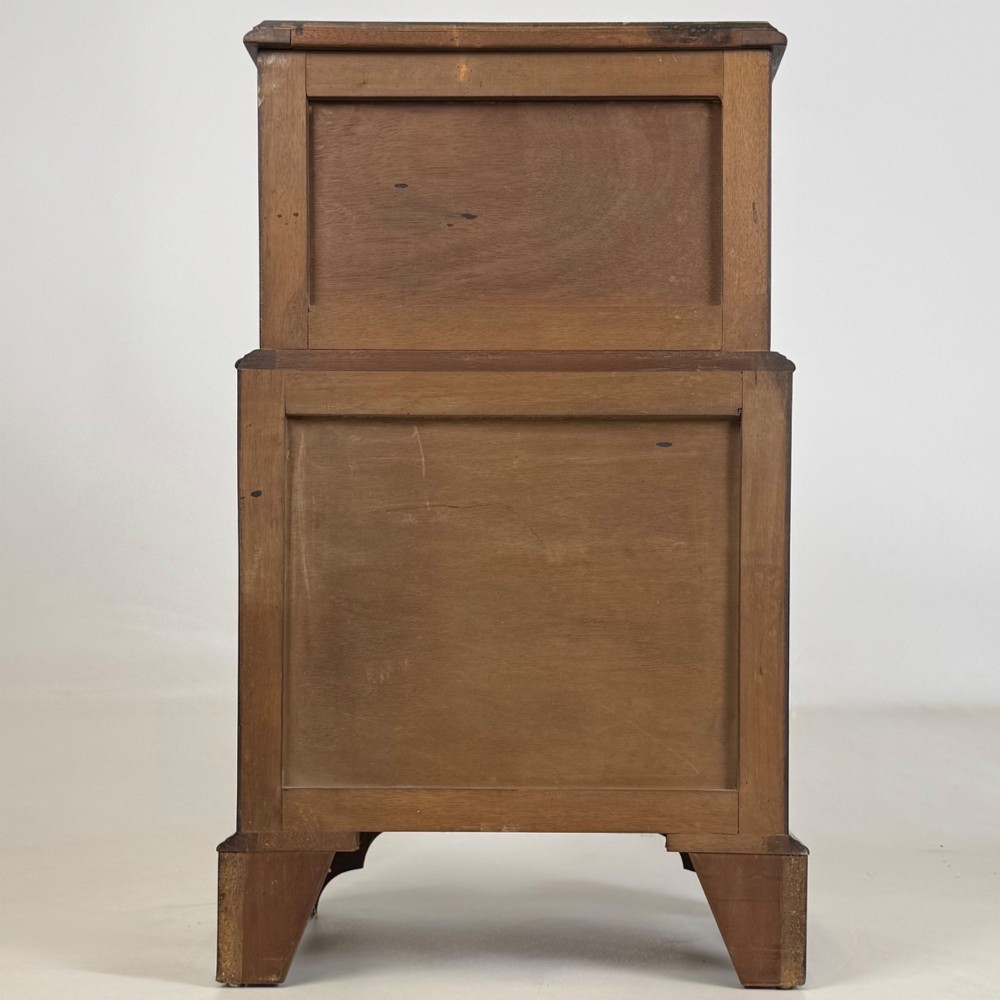 A small dark mahogany chest of drawers with five stacked drawers, brass ring handles, and bracket feet. View V
