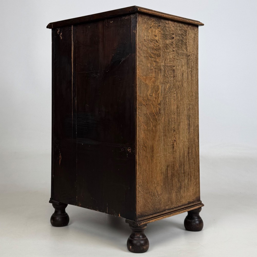 A small Edwardian carved dark oak cabinet with a single top drawer, a lower cupboard door, turned wooden knobs, and bun feet. View VII
